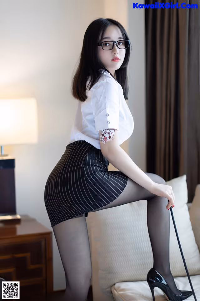 A woman in a white shirt and black skirt sitting on a couch.