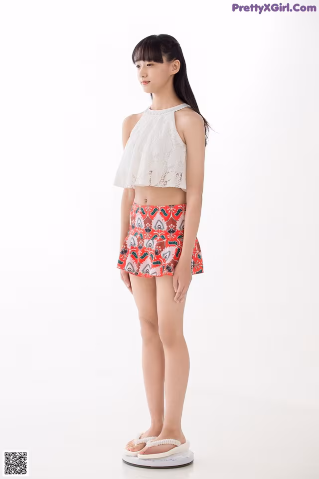 A young girl standing in front of a white background.
