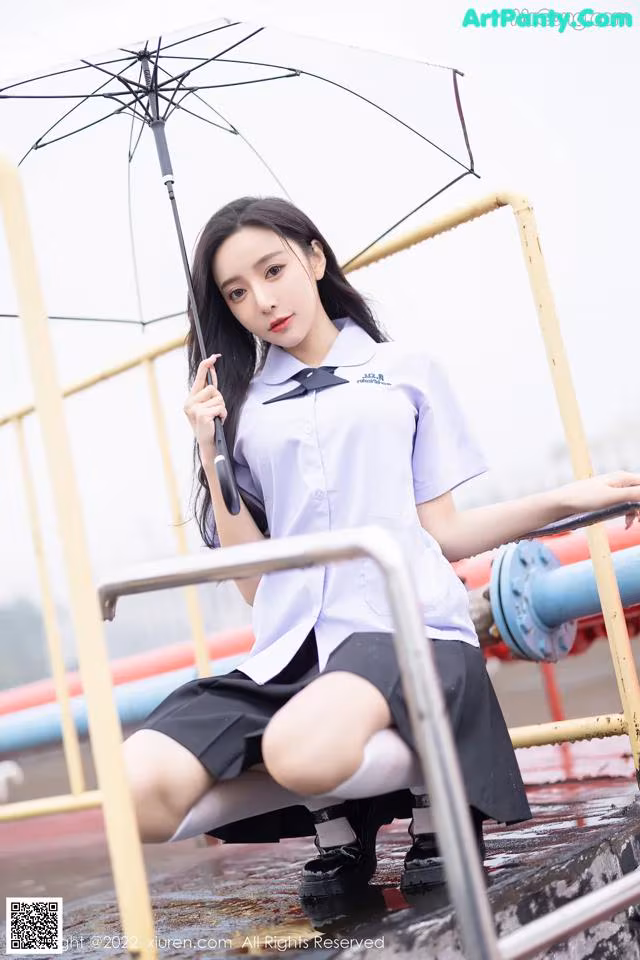 A woman in a school uniform holding an umbrella.