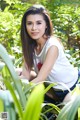 A woman sitting in the middle of a lush green forest.