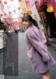 A woman in a purple coat is walking down the street.