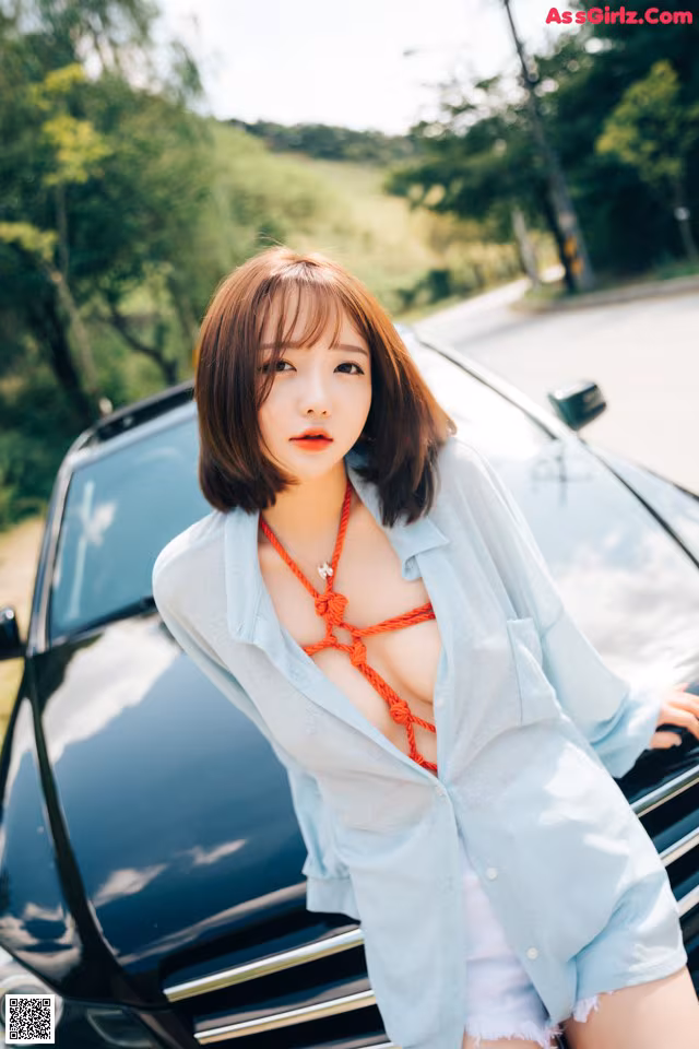 A woman standing next to a black car on a road.