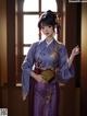 A woman in a purple kimono standing in front of a window.