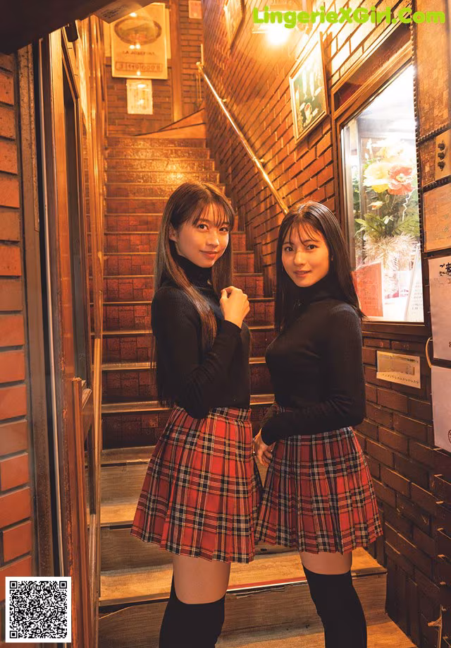 Two young women standing next to each other in front of a door.