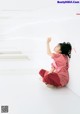 A little girl in a pink dress sitting on the floor.