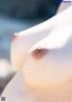 A close up of a nude woman's breasts on the beach.