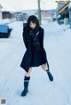 A woman in a school uniform is walking in the snow.