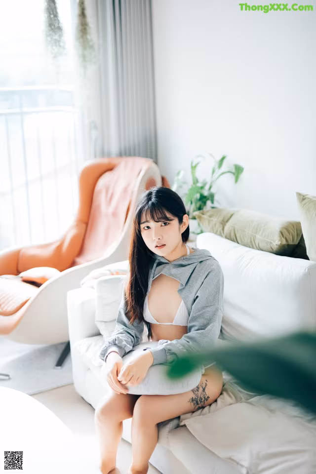 A woman sitting on a white couch in a living room.