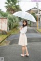 A woman standing in the middle of a street holding an umbrella.