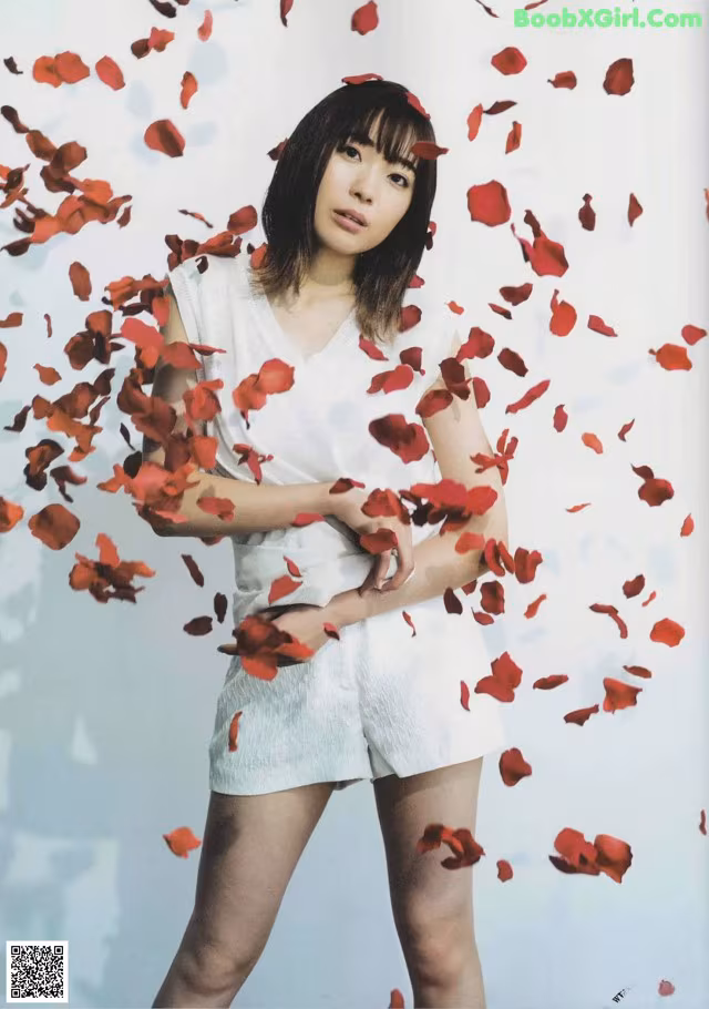 A woman standing in front of a bunch of red rose petals.