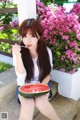 A woman sitting on the steps eating a slice of watermelon.