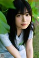 A young woman with long black hair sitting in the grass.