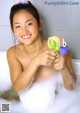 A young woman in a bathtub holding a toy water gun.