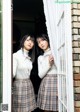 Two young women standing next to each other in front of a window.