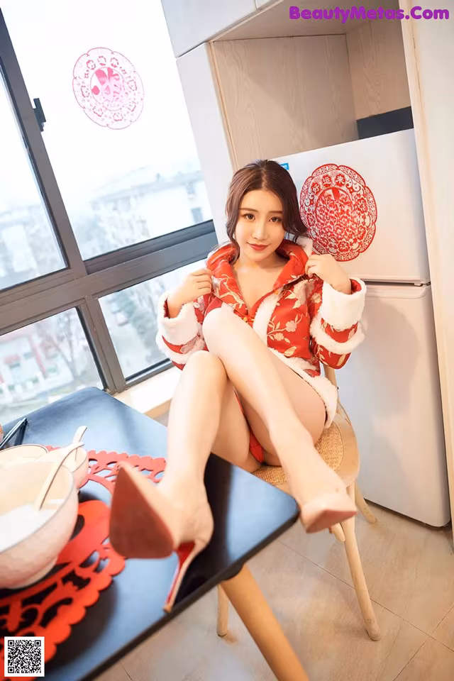 A woman sitting on a chair in a kitchen.
