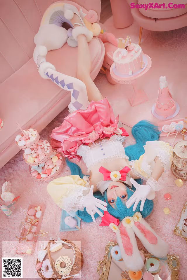 A woman laying on a pink couch surrounded by sweets.