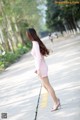 A woman in a pink dress is walking down the street.