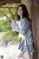 A woman in a school uniform leaning against a wall.