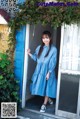 A woman standing in the doorway of a blue house.