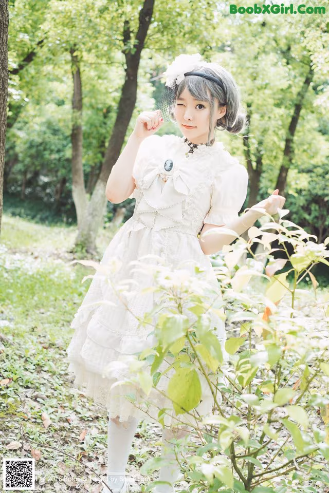A woman in a white dress standing in the woods.